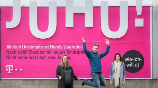 Grund zur Freude: Monika Ornik (EPAMEDIA), Emmanuel Buchholz (MediaCom) und Katharina Kröll (T-Mobile Austria) präsentieren die Formatsprengung am EPAMEDIA Plakat für die neue JUHU!-Kampagne © EPAMEDIA